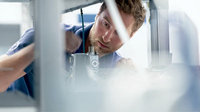 A man adjusts an industrial machine with focused attention.